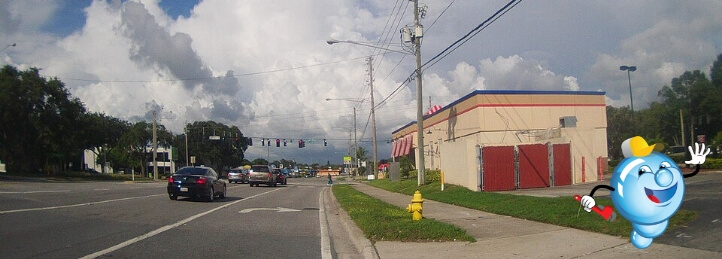 Street view in Dunedin, FL with cartoon plumber mascot promoting local plumbing services.